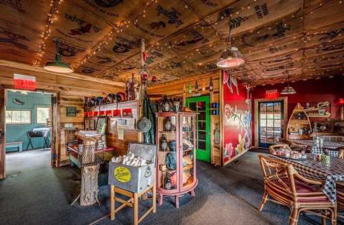 Cozy restaurant interior with wooden decor, colorful walls, and vintage items, illuminated by string lights.