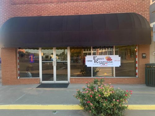 Front view of a storefront with a black awning and a sign for "First Response" on a brick building.