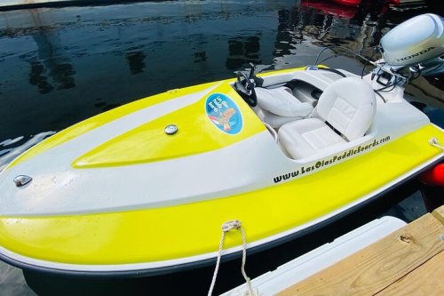 A bright yellow and white jet ski docked at a marina, reflecting in the calm water.