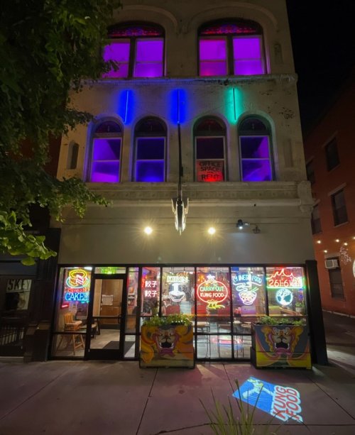 A brightly lit restaurant with colorful neon signs at night, featuring a vibrant facade and outdoor seating.