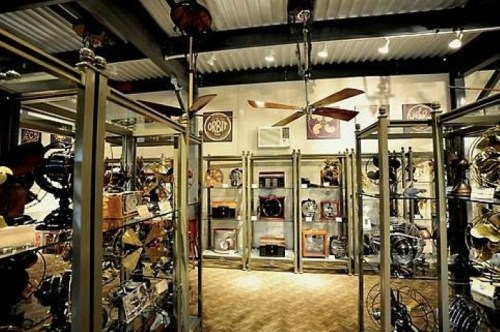 A vintage display room filled with various antique fans and memorabilia, featuring glass cases and wooden accents.