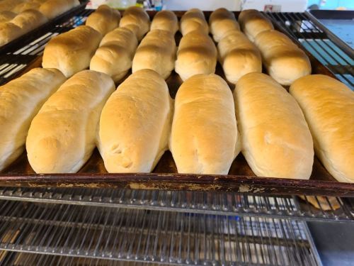 Freshly baked bread rolls arranged on a cooling rack, golden brown and fluffy.