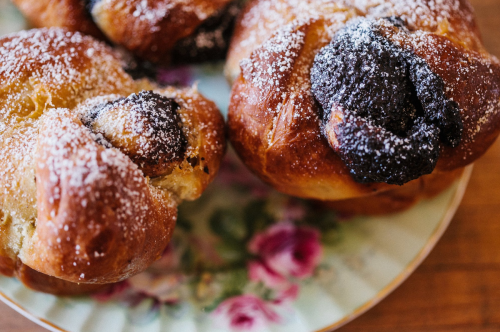 Close-up of sweet pastries dusted with powdered sugar on a floral plate.