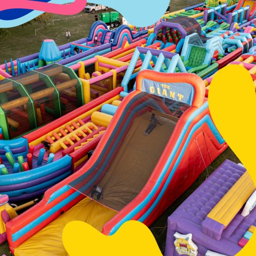 A colorful inflatable obstacle course and slide set up in a grassy area, featuring various shapes and sizes.