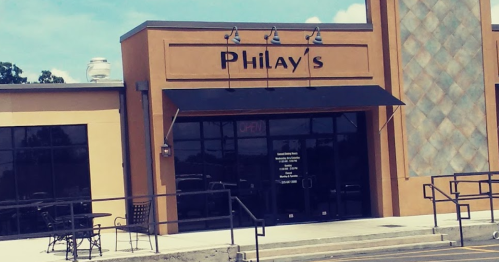 Exterior of Philay's restaurant with an open sign and outdoor seating area. Bright day with blue sky.