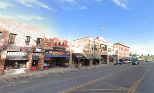 A charming street lined with historic buildings, shops, and an American flag waving in the breeze under a clear blue sky.