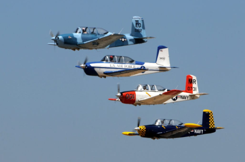 Four vintage aircraft flying in formation against a clear blue sky.
