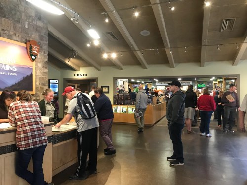 Visitors at a national park visitor center, engaging at information desks and browsing displays.