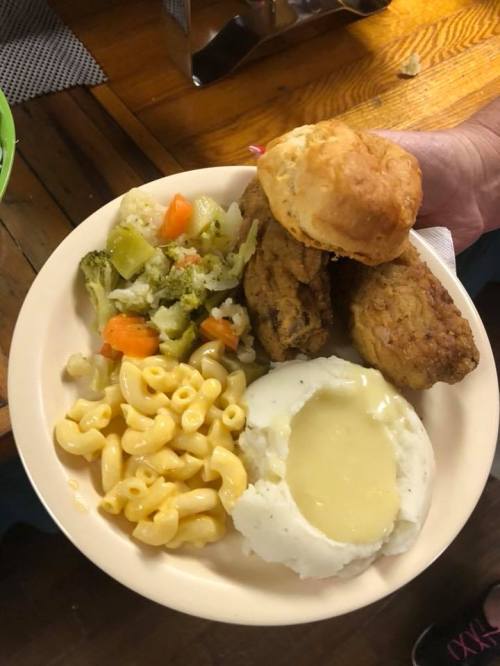 A plate of food featuring fried chicken, macaroni and cheese, mashed potatoes with gravy, mixed vegetables, and a biscuit.