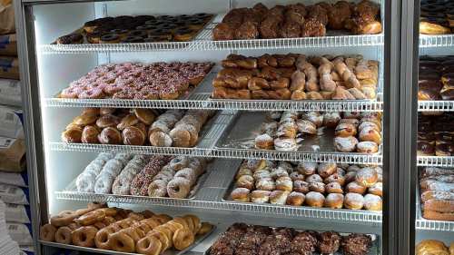 A display case filled with various types of donuts, including glazed, chocolate, and sprinkled varieties.