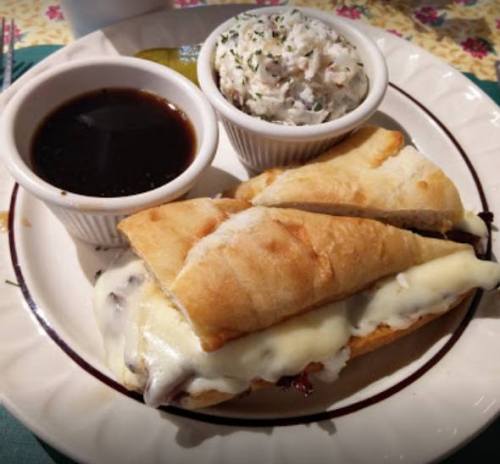 A plate with two toasted sandwiches filled with melted cheese, served with a side of coleslaw and dipping sauce.