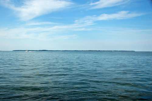 A calm blue sea under a clear sky, with a distant landmass visible on the horizon.