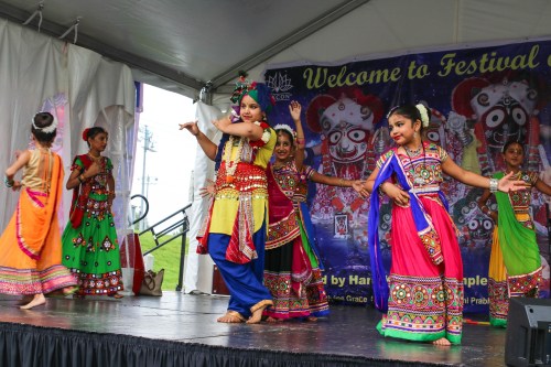 A group of young dancers in colorful traditional outfits perform on stage at a cultural festival.