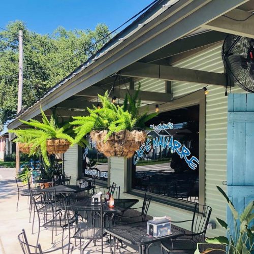 Exterior of a café with hanging ferns, outdoor seating, and a bright sign reading "Café Aware."