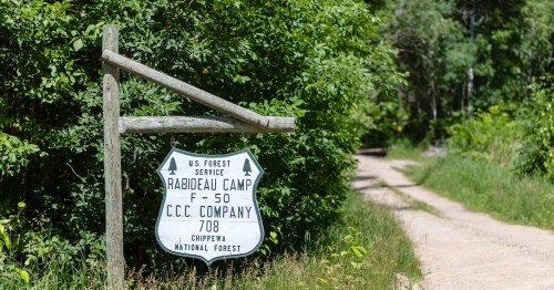 Sign for Rabideau Camp, F-50, CCC Company 708, located in Chippewa National Forest, surrounded by greenery.