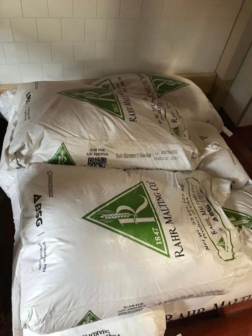 Two large bags of malted grain stacked on a wooden surface, labeled with the Rahr Malting Co. logo.