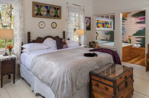 Cozy bedroom with a large bed, wooden furniture, and colorful stained glass windows. Warm, inviting atmosphere.