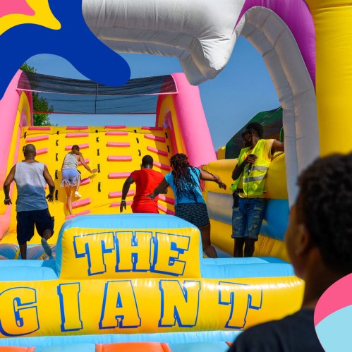 People climbing a colorful inflatable slide at a fun outdoor event on a sunny day.