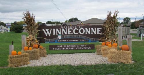 Welcome sign for Winneconne, featuring pumpkins and hay bales, celebrating its baseball championship history.