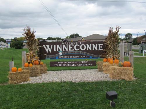 Welcome sign for Winneconne, featuring pumpkins and hay bales, celebrating its baseball championship history.