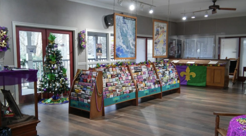 A brightly lit shop interior with greeting card displays, a decorated Christmas tree, and festive decorations.