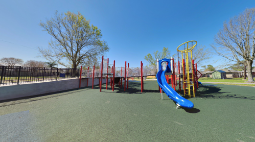 Colorful playground with a blue slide, climbing structures, and a grassy area under a clear blue sky.