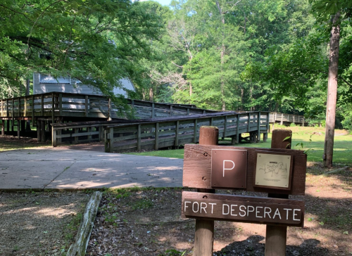 A wooden ramp leads to a building in a wooded area, with a sign reading "Fort Desperate" in the foreground.