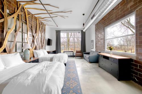 A modern hotel room with two beds, a sofa, and large windows, featuring unique wooden decor and a cozy atmosphere.