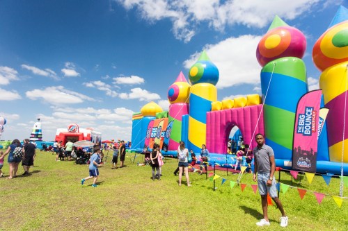 A colorful inflatable bounce house event with people enjoying the attractions on a sunny day.