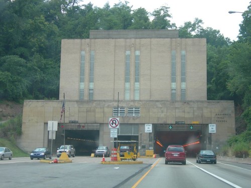 Entrance to the Achievel Tunnel, featuring a large, art deco-style building and traffic signals.