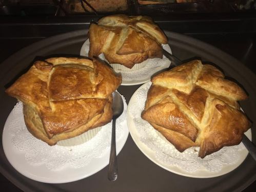 Three golden-brown pastries on white plates, each with a crisscross pattern on top, served on a tray.