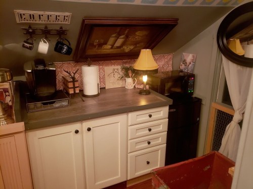 Cozy kitchen nook with coffee maker, microwave, lamp, and decorative wall art in a warm, inviting space.