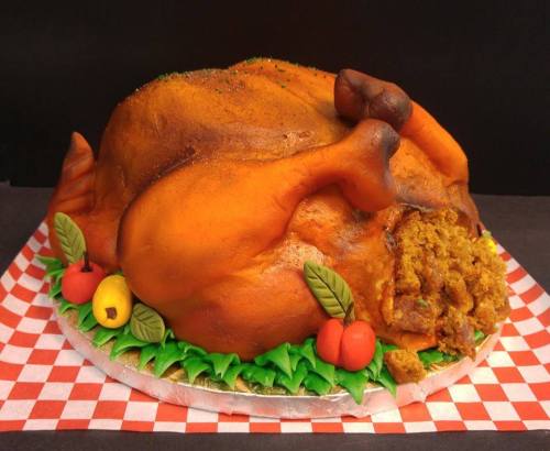 A realistic cake shaped like a roasted turkey, complete with colorful decorations of vegetables and stuffing.