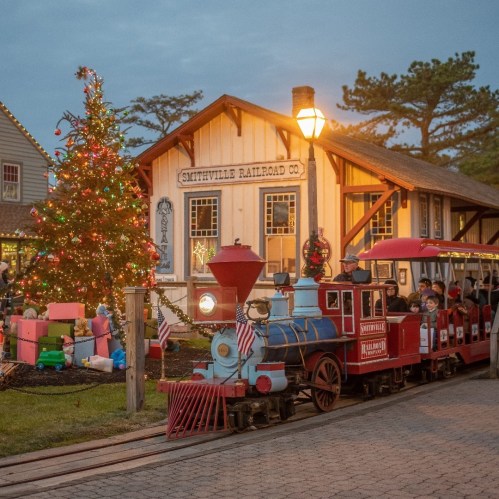 A festive train at Smithville Railroad Co. with a decorated Christmas tree and colorful gifts nearby.