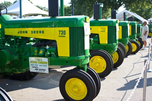 A row of vintage John Deere 730 diesel tractors displayed at an outdoor event.