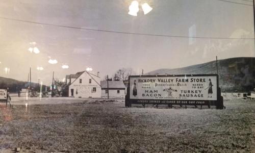 Black and white photo of Hickory Valley Farm Store with a large sign advertising ham, turkey, bacon, and sausage.