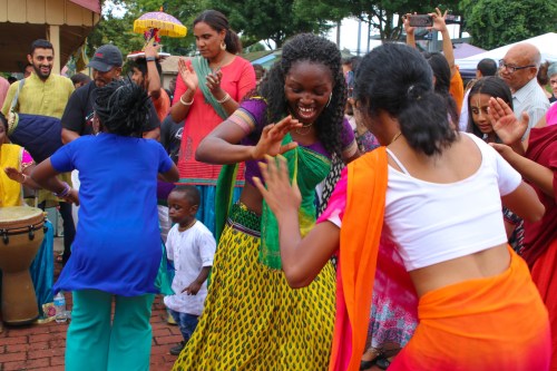 A lively group of people dancing joyfully at a cultural festival, wearing colorful traditional attire.