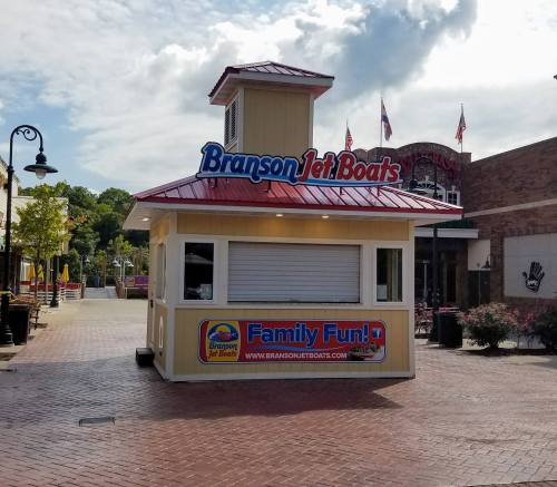 A small ticket booth for Branson Jet Boats, featuring a red roof and signage promoting family fun.