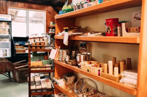 A wooden shelf filled with various craft supplies and small items in a cozy store setting.