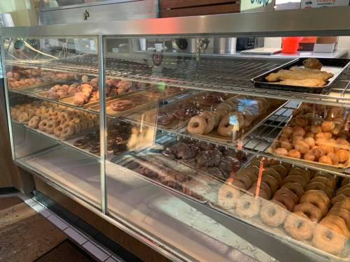 A display case filled with a variety of donuts, including glazed, chocolate, and powdered options.