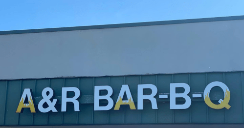 Sign for A&R Bar-B-Q against a clear blue sky, featuring bold white letters with yellow accents.