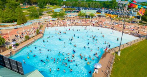 Aerial view of a busy water park pool filled with people enjoying the water on a sunny day.