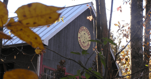 A rustic building with a sign reading "Foxhunters," surrounded by autumn leaves and trees.