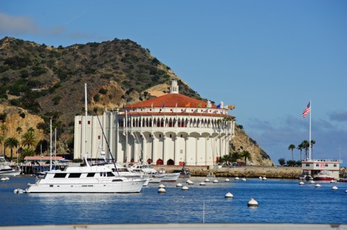 Catalina Island's iconic Casino building with boats in the harbor and a mountainous backdrop under a clear blue sky.