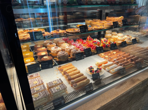 A display case filled with various pastries, including fruit tarts, éclairs, and croissants, all beautifully arranged.
