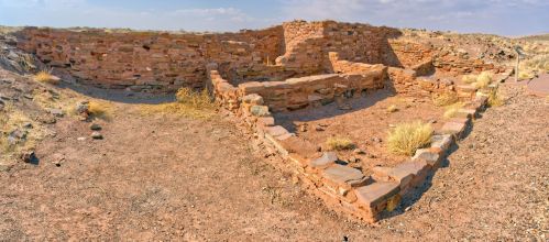 Ruins of an ancient stone structure in a dry, arid landscape with sparse vegetation and a clear sky.