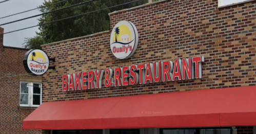 Sign for Gually's Bakery & Restaurant on a brick building with a red awning.