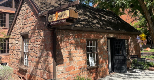 A charming stone building with a sign reading "Beef Sweet" and outdoor seating, surrounded by trees.