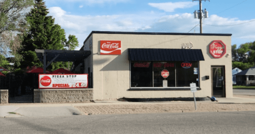 A pizza shop with a Coca-Cola sign, featuring an "Open" sign and a special offer displayed outside.