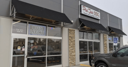 Exterior of a storefront with awnings, featuring signs for "Bud Light" and "Phat Jacks BBQ" in a commercial area.